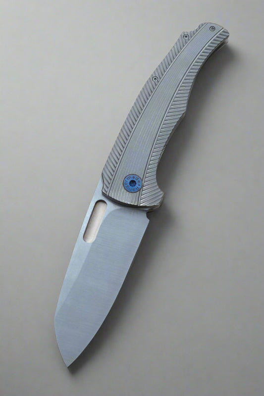 Folding knife with a metallic blade and textured handle on a beige background